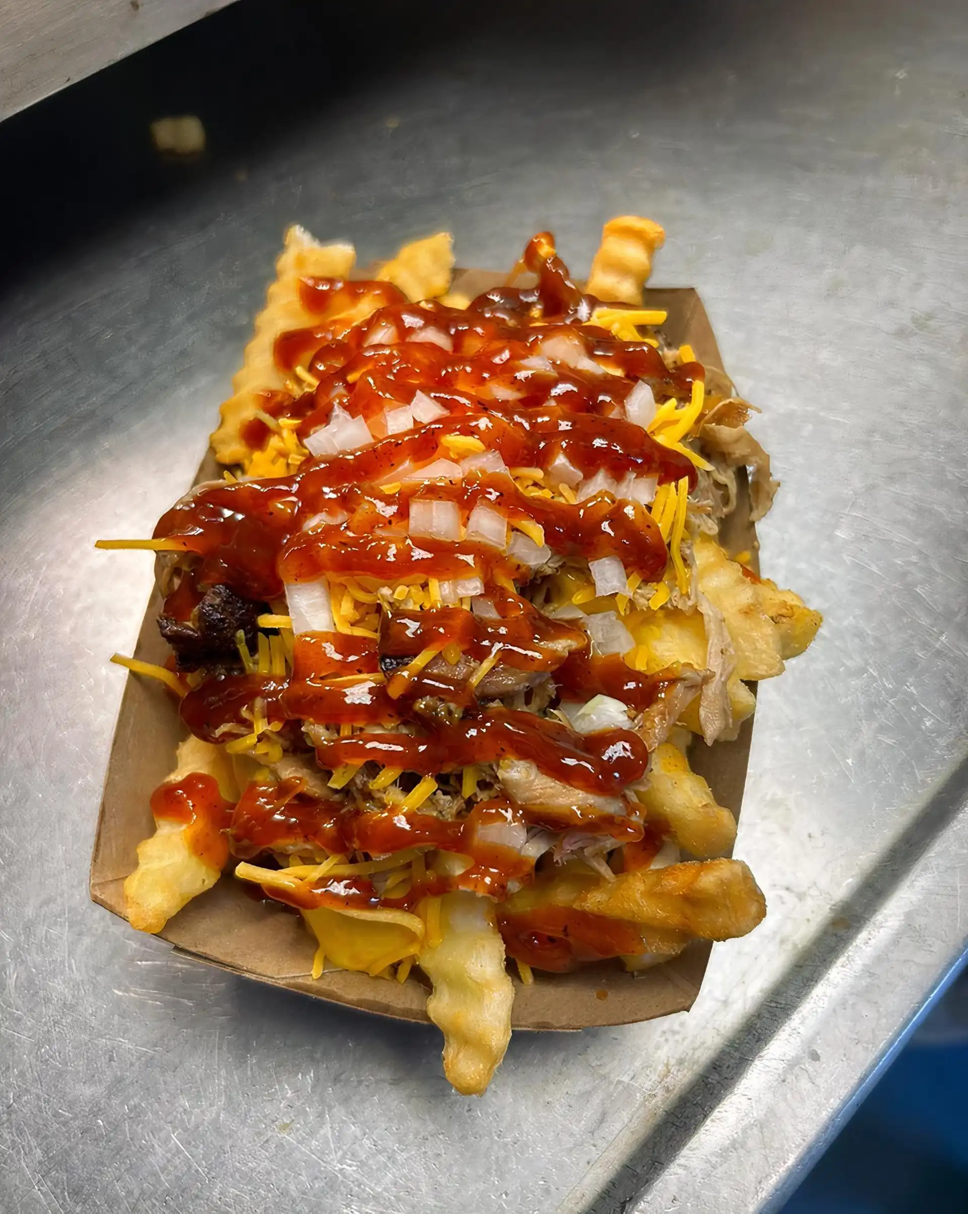 Crinkle Cut Fries with House Smoked Pulled Pork, Nacho Cheese, Shredded Cheese, Onion, Pickle, and House Made BBQ Sauce