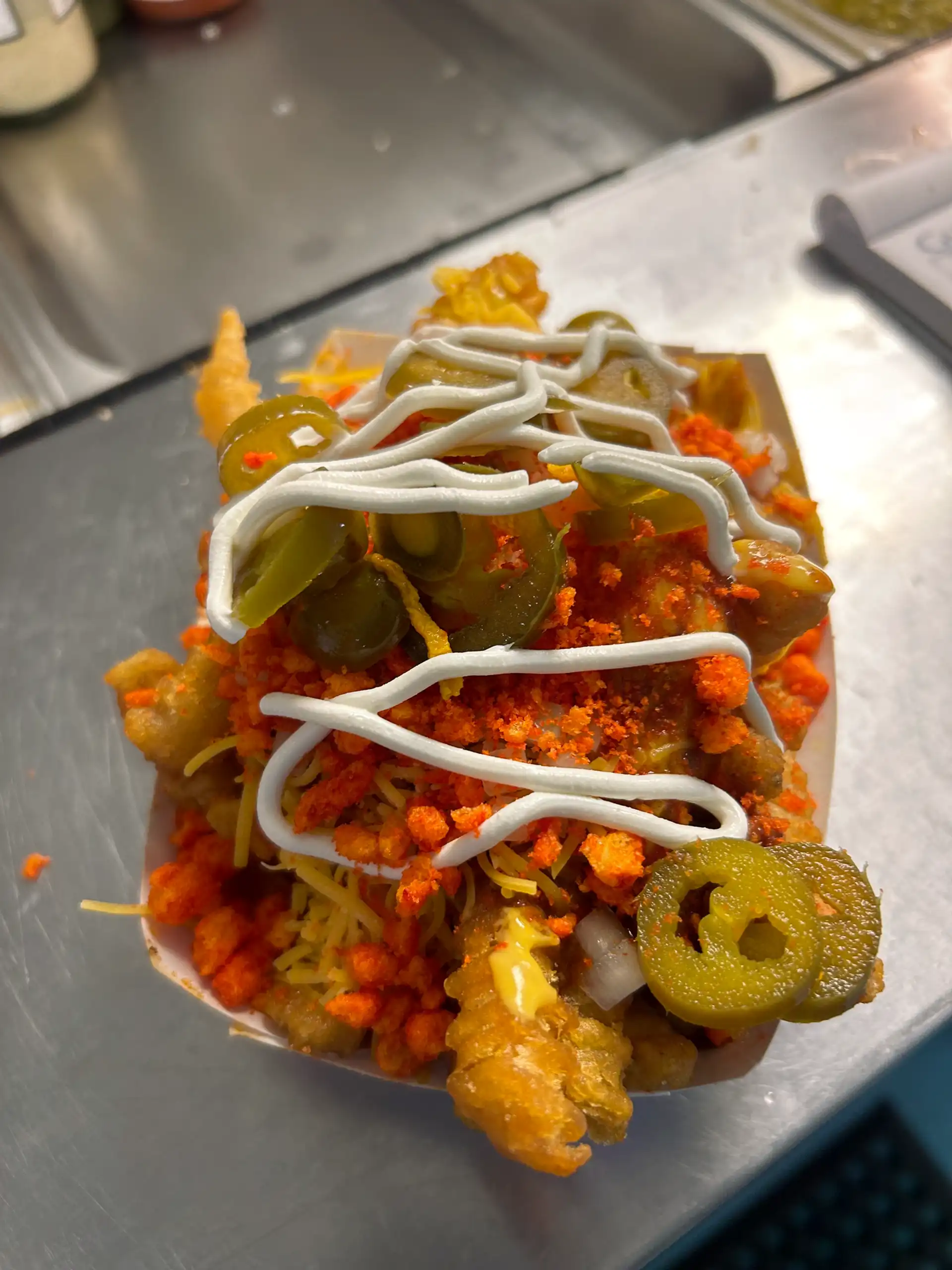 Crinkle Cut French Fries with Chili, Nacho Cheese, Shredded Cheese, Onion, Jalapeño, Flaming Hot Cheeto Dust, and Sour Cream