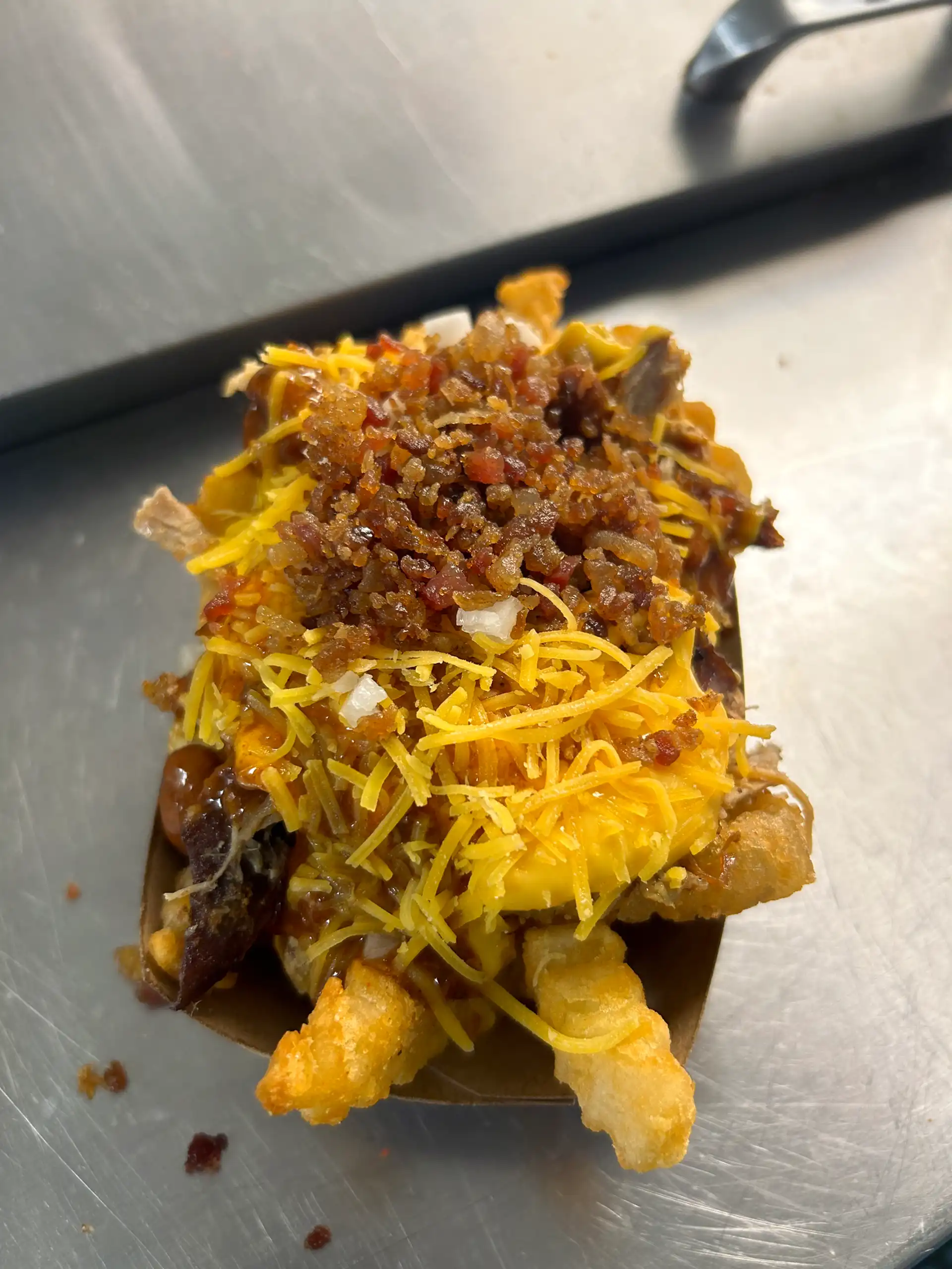 Crinkle Cut French Fries with it all! Pulled Pork, Nacho Cheese, Chili, Shredded Cheese, Bacon Bits, Onion, and Jalapeño