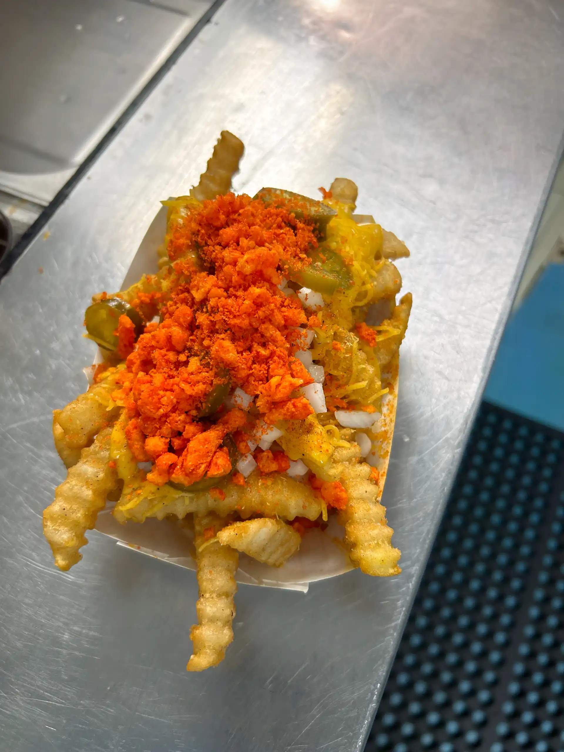 Crinkle Cut French Fries with Nacho Cheese, Shredded Cheese, Onion, Jalapeño, Flaming Hot Cheeto Dust and Reaper Powder