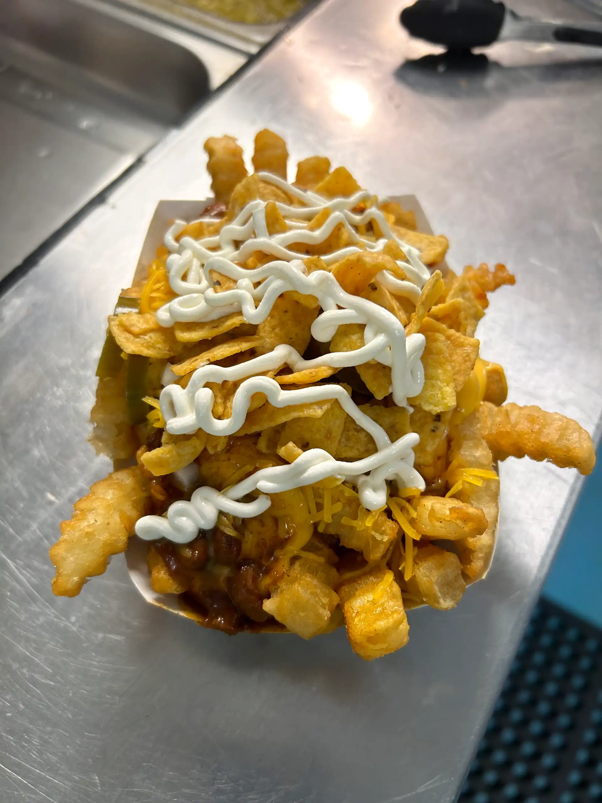Crinkle Cut French Fries with Chili, Nacho Cheese, Shredded Cheese, Onion, Jalapeño, and Sour Cream